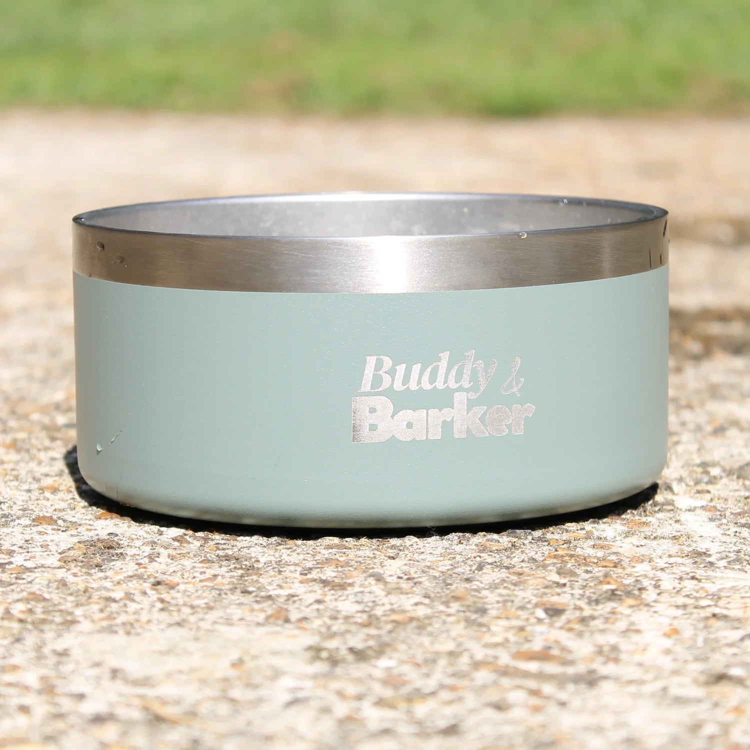 Dog bowl with 'Buddy & Barker' branding on a concrete surface.