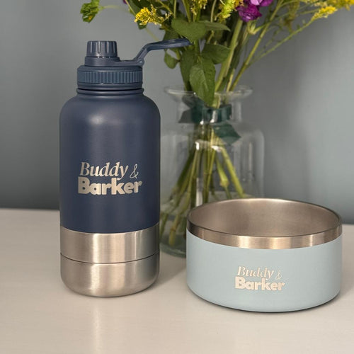 Navy water bottle and light blue bowl with 'Buddy & Barker' branding on a neutral background.